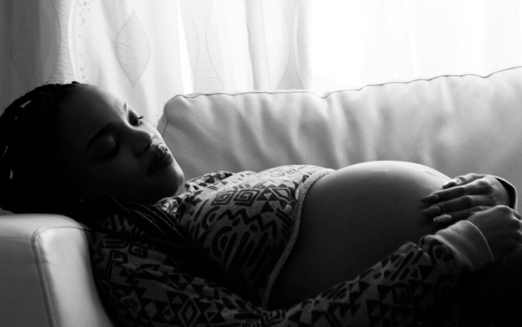 Black African-American pregnant woman laying on couch, anxiety, post-partum depression, postpartum depression, perinatal mental health disorder, maternal mental health, mom, pregnancy, baby, newborn, therapy, counseling, mood disorder